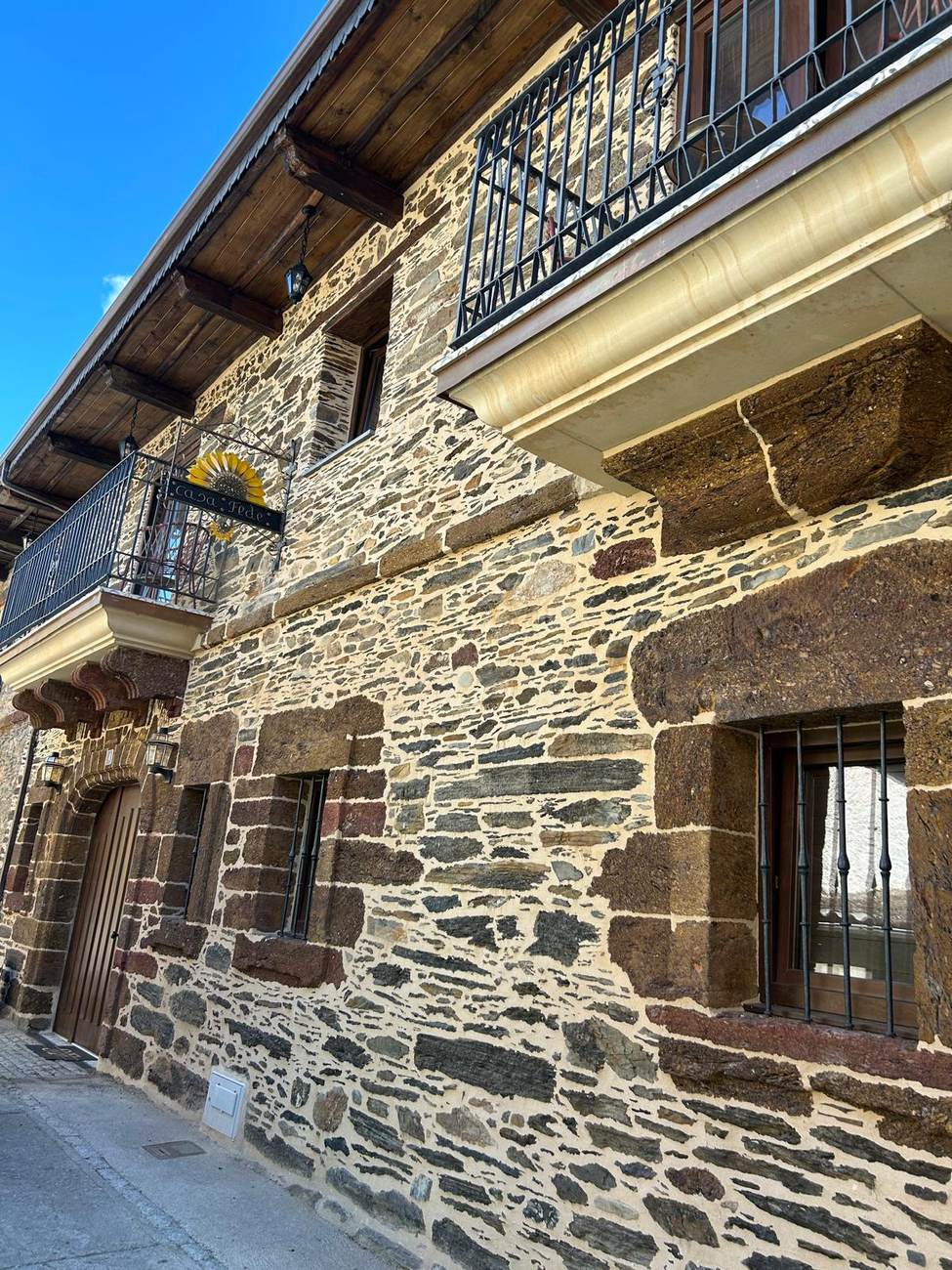 Fachada de piedra de Casa Fede, con balcones de forja, en Puente de Domingo Flórez