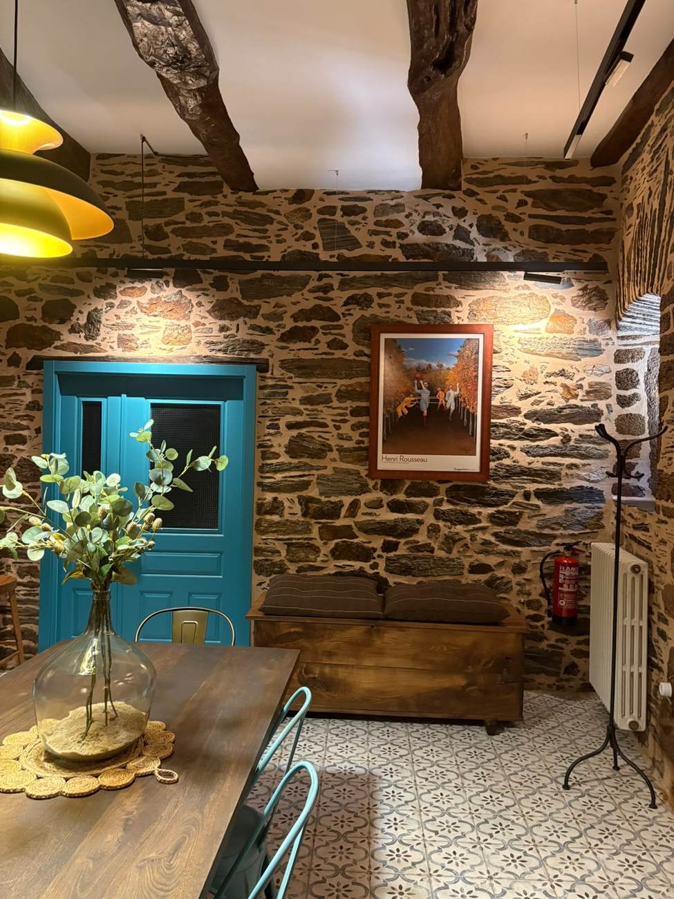 Banco baúl y arte junto a la puerta turquesa